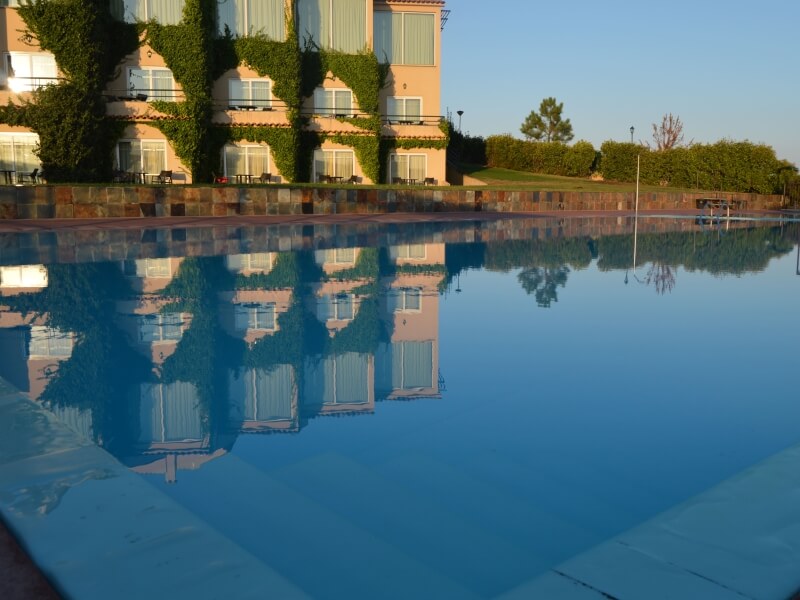 Edifício do hotel reflectido na água da piscina ao amanhecer